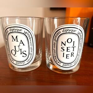 Two empty Diptyque luxury candle vessels: Noisetier snd Maquis.